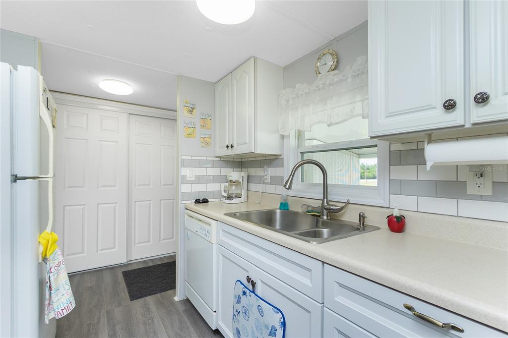 A kitchen features white cabinets, a double-basin sink, subway tile backsplash, and light-colored countertops — 7598 RATAN CIRCLE, PORT CHARLOTTE, FL