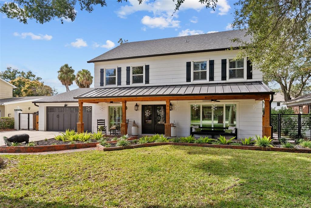 A two-story white house features a dark metal roof, wooden porch posts, and black shutters — 1511 S SHERIDAN FOREST DRIVE, TAMPA, FL