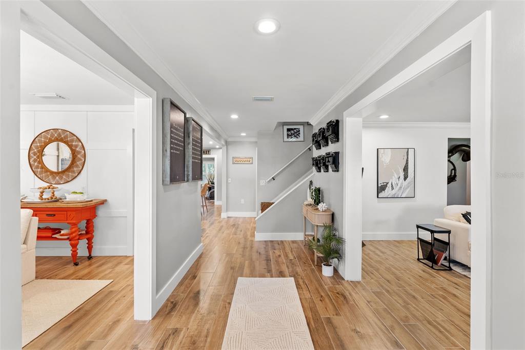 A bright hallway with wood-look tile flooring leads to a staircase and adjacent living spaces — 1511 S SHERIDAN FOREST DRIVE, TAMPA, FL
