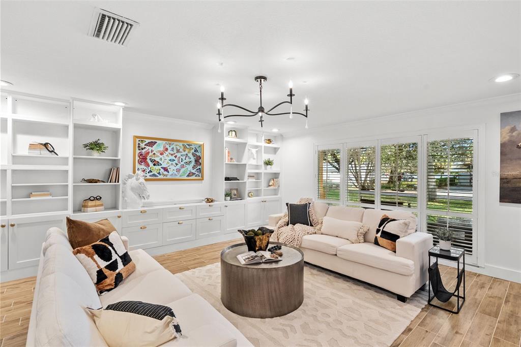 A bright living room features white built-in shelving, two sofas, a round coffee table, and shutters — 1511 S SHERIDAN FOREST DRIVE, TAMPA, FL