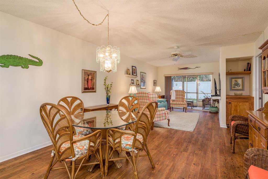 A dining area with a glass table and wicker chairs opens into a living room — 952 VIRGINIA STREET UNIT 105, DUNEDIN, FL