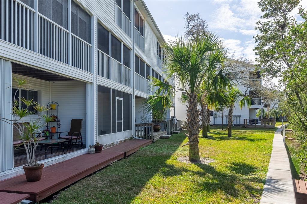 A multi-story apartment building with screened-in porches, a wooden deck, and a grassy yard — 9920 INDIAN KEY TRAIL UNIT 29, SEMINOLE, FL