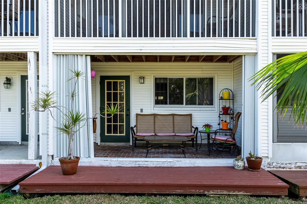 A ground-level patio with a brick floor, wicker furniture, and a wooden deck — 9920 INDIAN KEY TRAIL UNIT 29, SEMINOLE, FL
