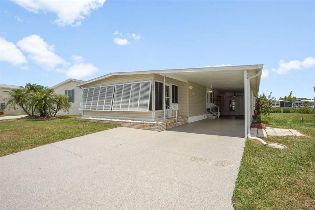 A single-story mobile home with a concrete driveway, carport, and white louvered shutters — 654 BLACKBURN BOULEVARD, NORTH PORT, FL