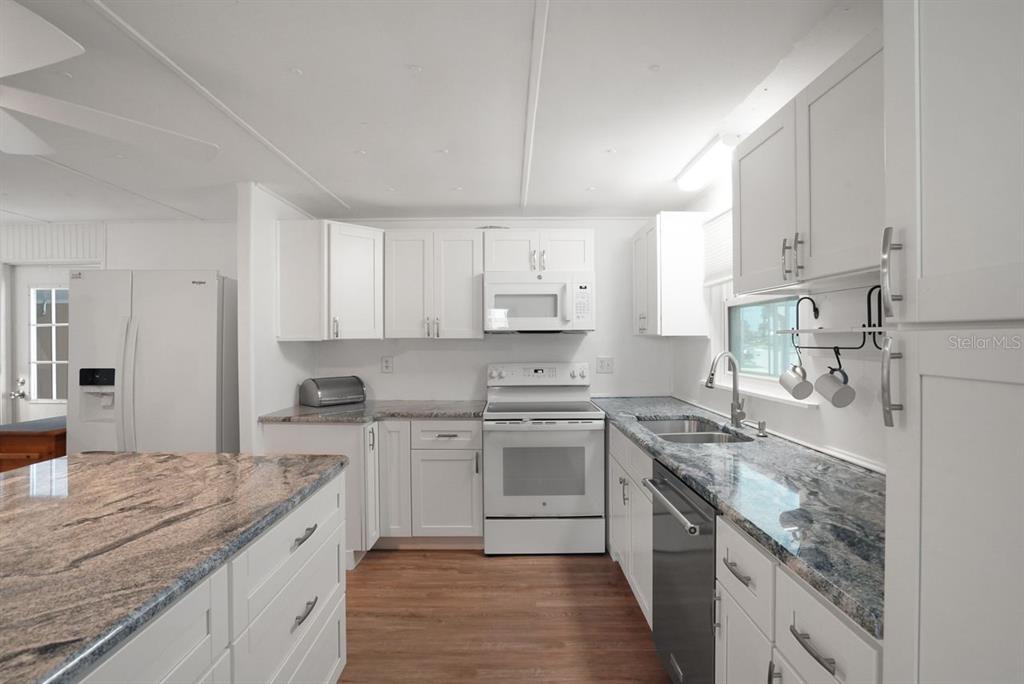 A kitchen with white cabinets, granite countertops, stainless steel appliances, and wood-look flooring — 654 BLACKBURN BOULEVARD, NORTH PORT, FL