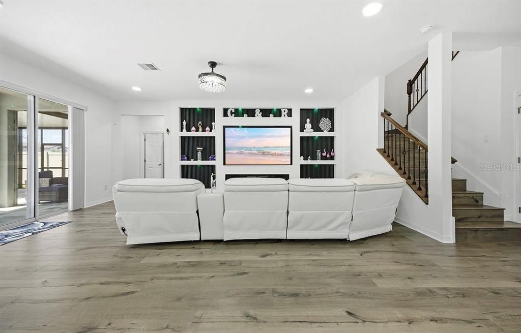 A living room features a white sectional sofa facing a built-in media wall with shelving — 7792 NOTCHED PINE BEND, WESLEY CHAPEL, FL