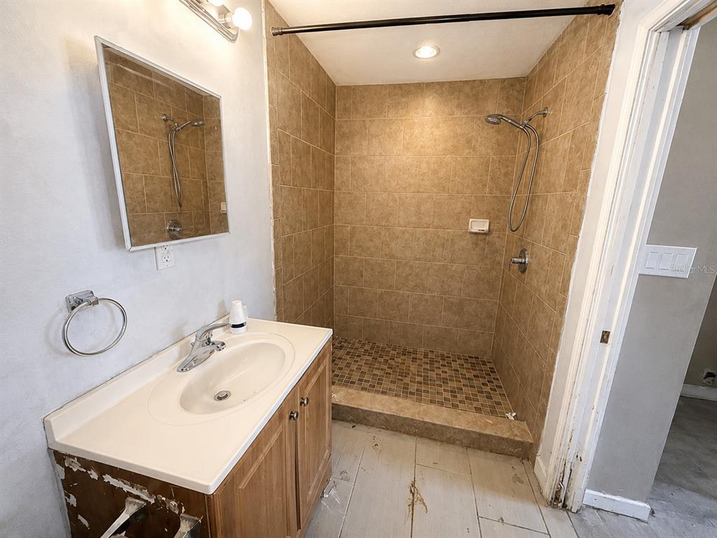A bathroom features a wood vanity, a wall-mounted mirror, and a tiled walk-in shower — 508 OAKLAND ROAD, AUBURNDALE, FL
