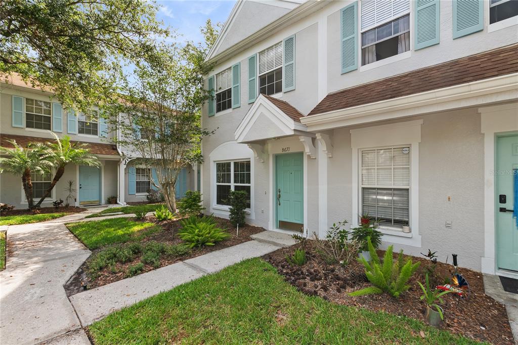 A two-story townhouse exterior features light gray stucco walls, light blue shutters, and a teal door — 8671 HUNTERS KEY CIRCLE UNIT 8671, TAMPA, FL