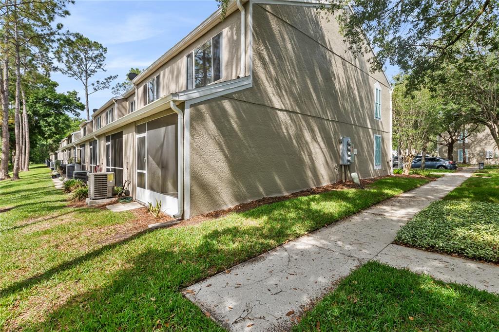 A side view of a multi-unit townhouse building with screened-in patios and a concrete walkway — 8671 HUNTERS KEY CIRCLE UNIT 8671, TAMPA, FL