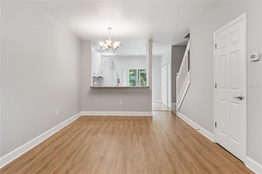 A dining area with wood-look flooring, a breakfast bar, and a staircase with white railings — 8671 HUNTERS KEY CIRCLE UNIT 8671, TAMPA, FL