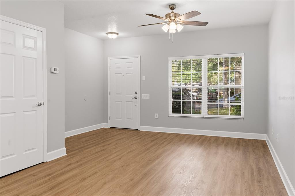 An empty room with light gray walls, wood-look flooring, a ceiling fan, and a window — 8671 HUNTERS KEY CIRCLE UNIT 8671, TAMPA, FL