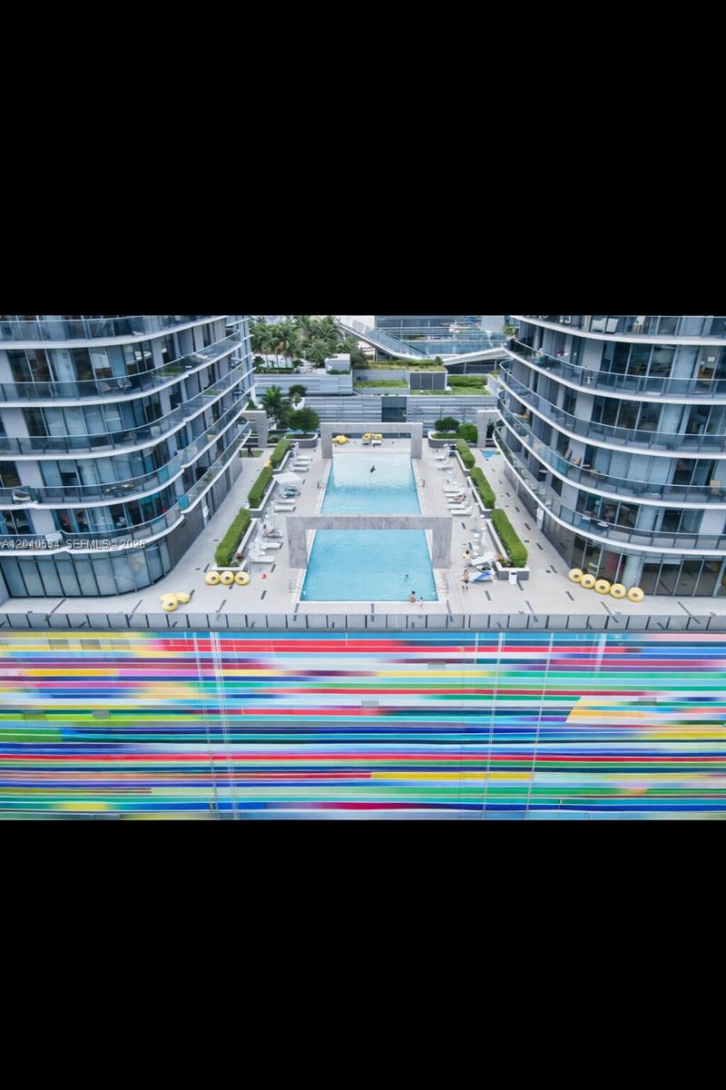An aerial view shows a swimming pool situated between two modern high-rise apartment buildings — 45 SW 9th St # 1004, Miami FL 33130, MIAMI, FL
