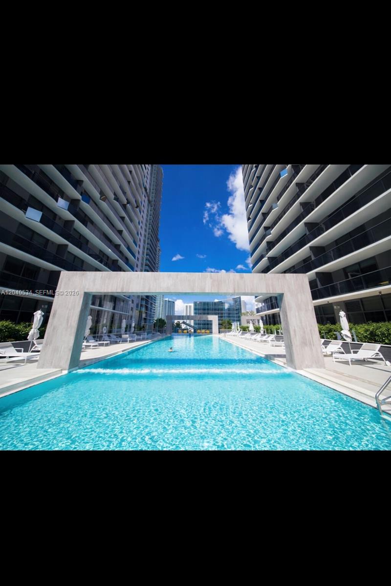 A long outdoor swimming pool is framed by two modern high-rise apartment buildings — 45 SW 9th St # 1004, Miami FL 33130, MIAMI, FL