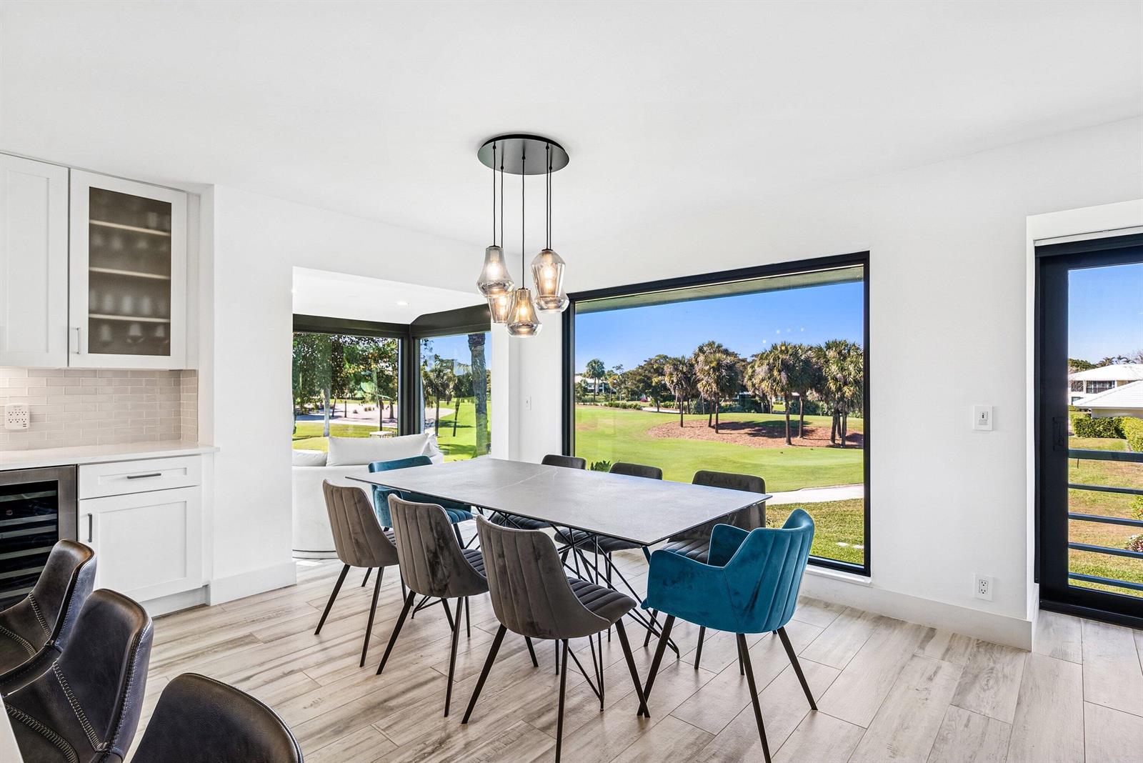 A dining room with a stone table, modern chairs, and large windows overlooking a golf course — 3667 Quail Ridge Drive N # B, Boynton Beach FL 33436, BOYNTON BEACH, FL