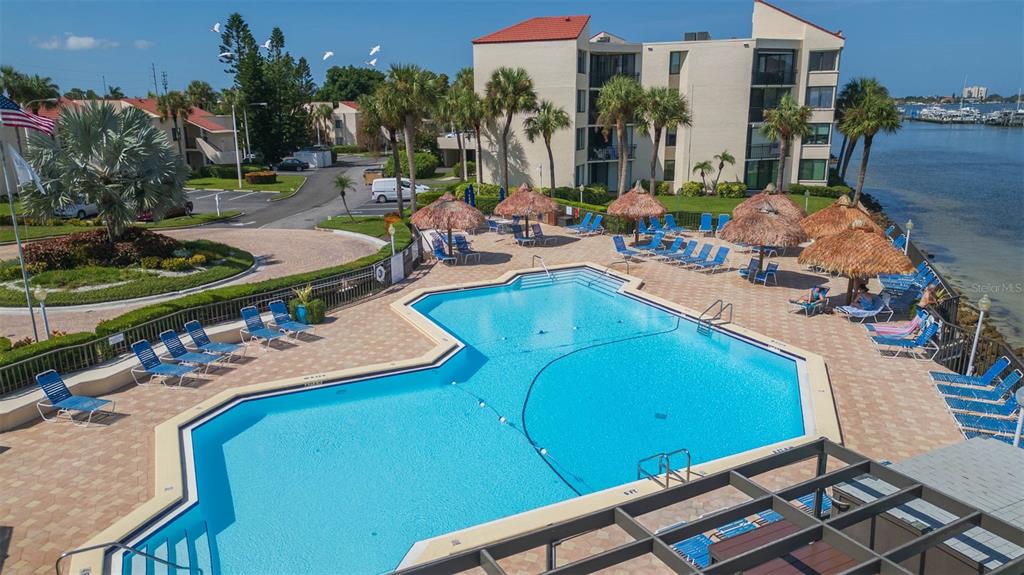 An elevated view of a swimming pool with lounge chairs and tiki umbrellas near water — 5736 PUERTA DEL SOL BOULEVARD S UNIT 254, ST PETERSBURG, FL