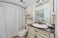 A bathroom features a white shower curtain, a toilet, and a vanity with a vessel sink — 5736 PUERTA DEL SOL BOULEVARD S UNIT 254, ST PETERSBURG, FL