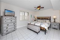A bedroom features a wooden bed frame, a matching dresser, and light-colored tile flooring — 5736 PUERTA DEL SOL BOULEVARD S UNIT 254, ST PETERSBURG, FL