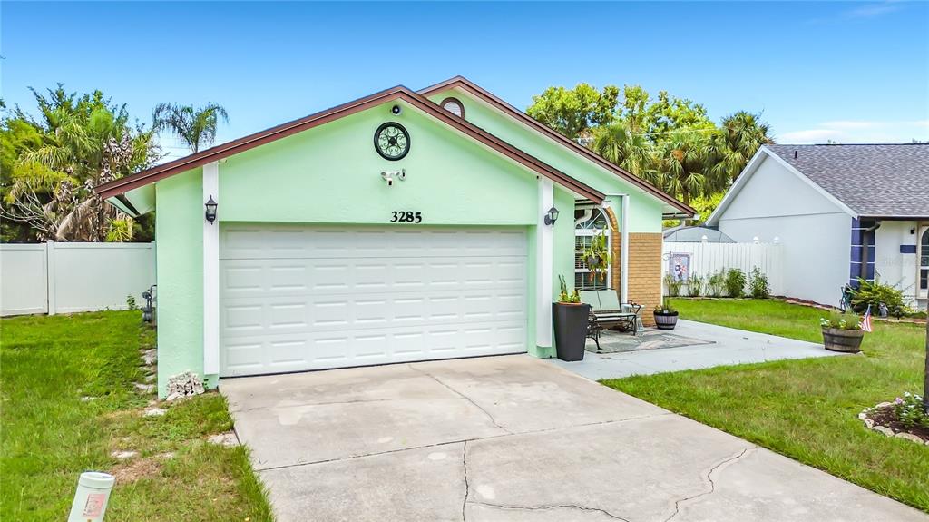A light green house with a two-car garage, a concrete driveway, and a small patio — 3285 SMOKE SIGNAL CIRCLE, KISSIMMEE, FL