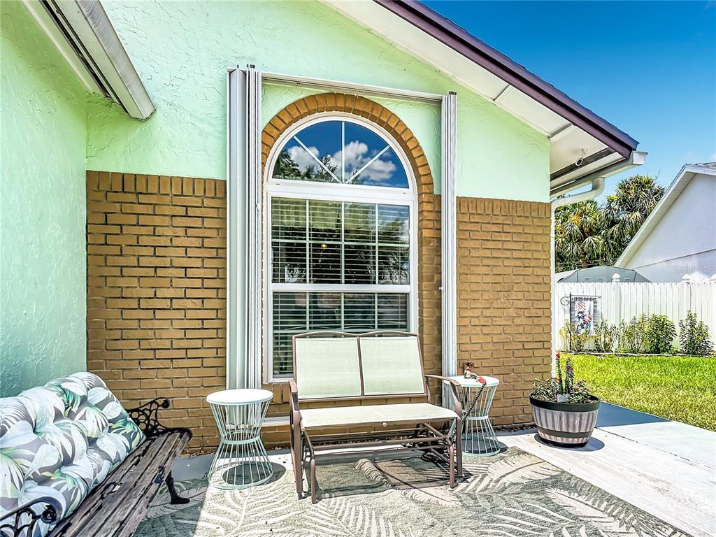 A patio area features a bench, two side tables, and a window with hurricane shutters — 3285 SMOKE SIGNAL CIRCLE, KISSIMMEE, FL