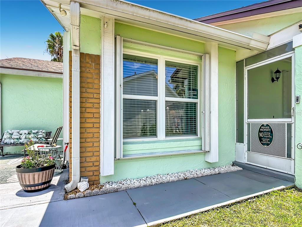 A light green house exterior features a brick pillar, a window, and a screened door — 3285 SMOKE SIGNAL CIRCLE, KISSIMMEE, FL