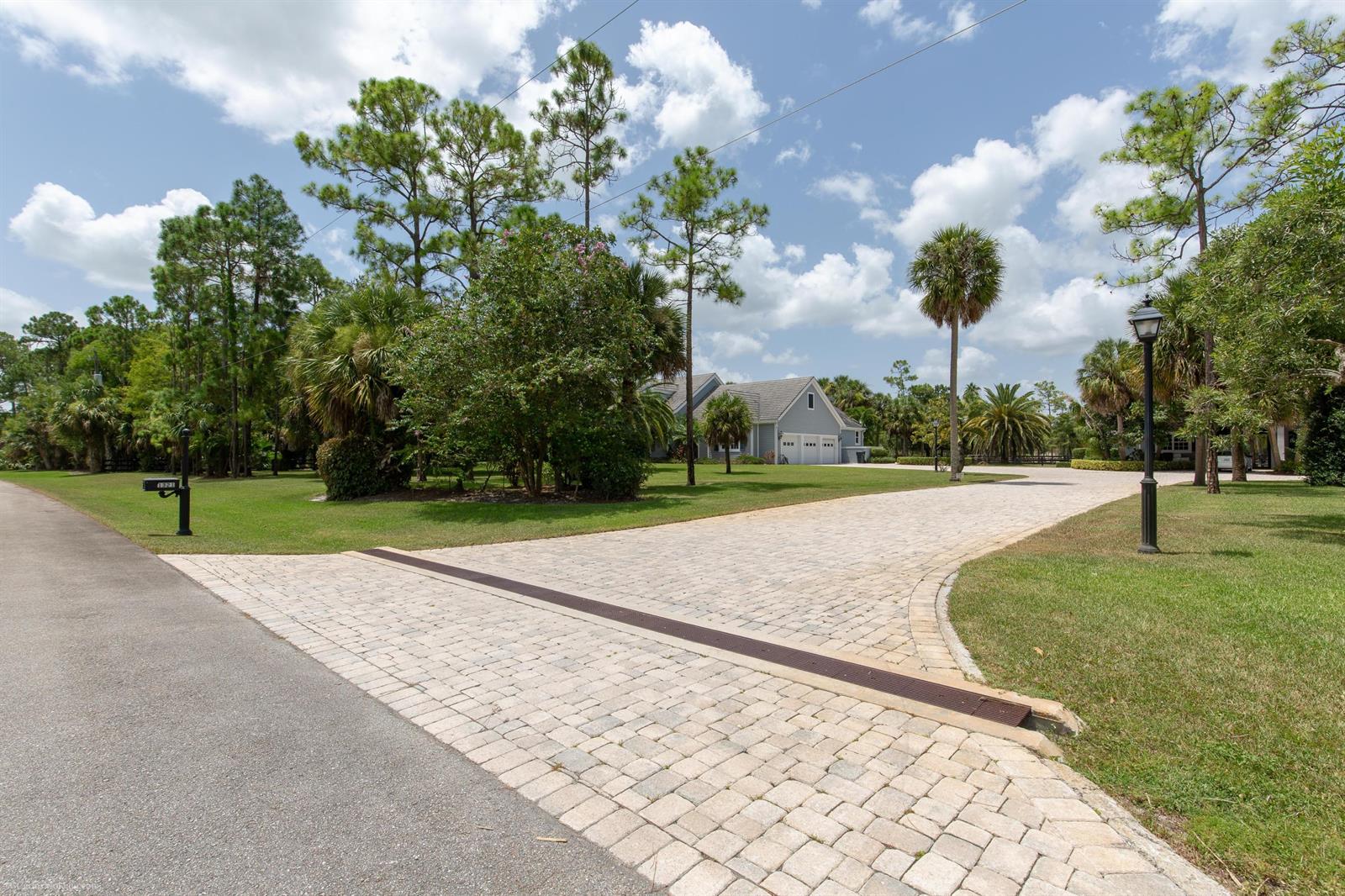 A paved driveway leads to a house surrounded by trees and a lawn — 1321 Pelham Road, Wellington FL 33414, WELLINGTON, FL