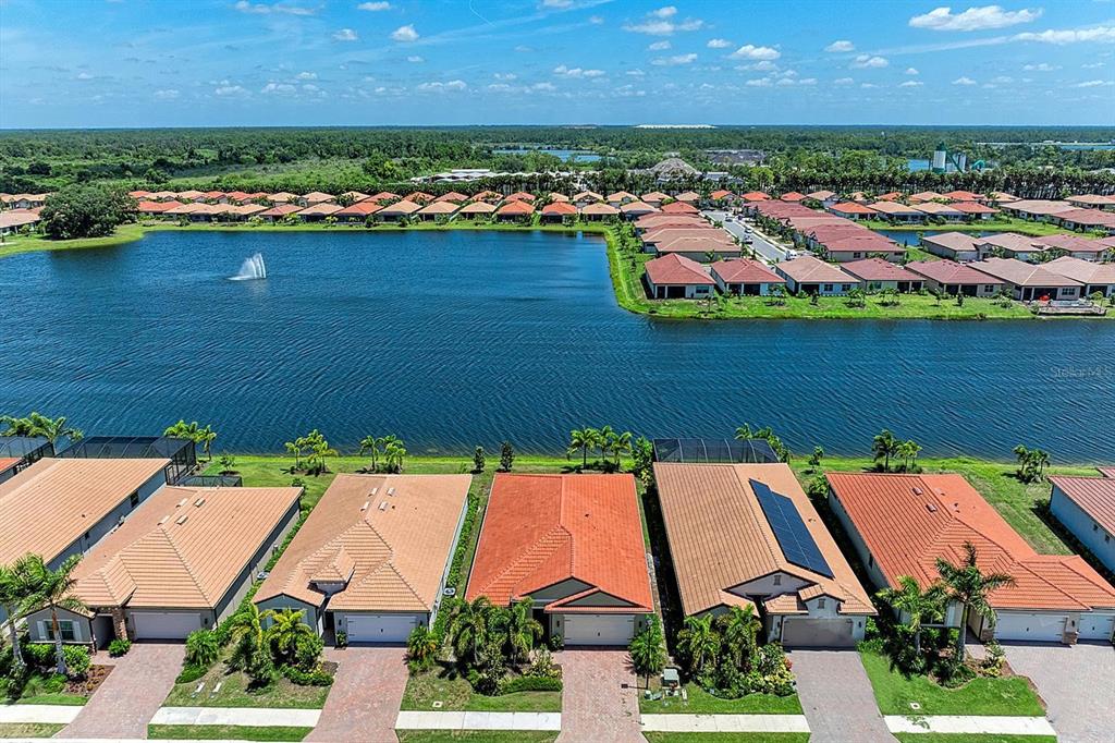 An aerial view shows a row of houses with tiled roofs bordering a large lake — 244 VILLORESI BOULEVARD, NOKOMIS, FL