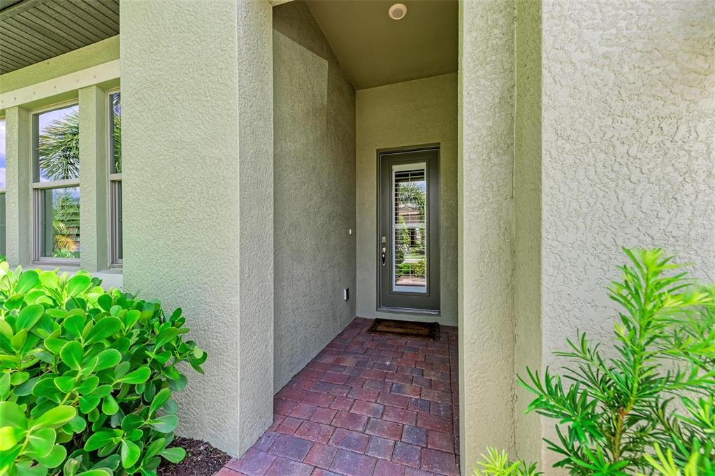 A covered entryway features a brick paver floor and a glass-paneled front door — 244 VILLORESI BOULEVARD, NOKOMIS, FL