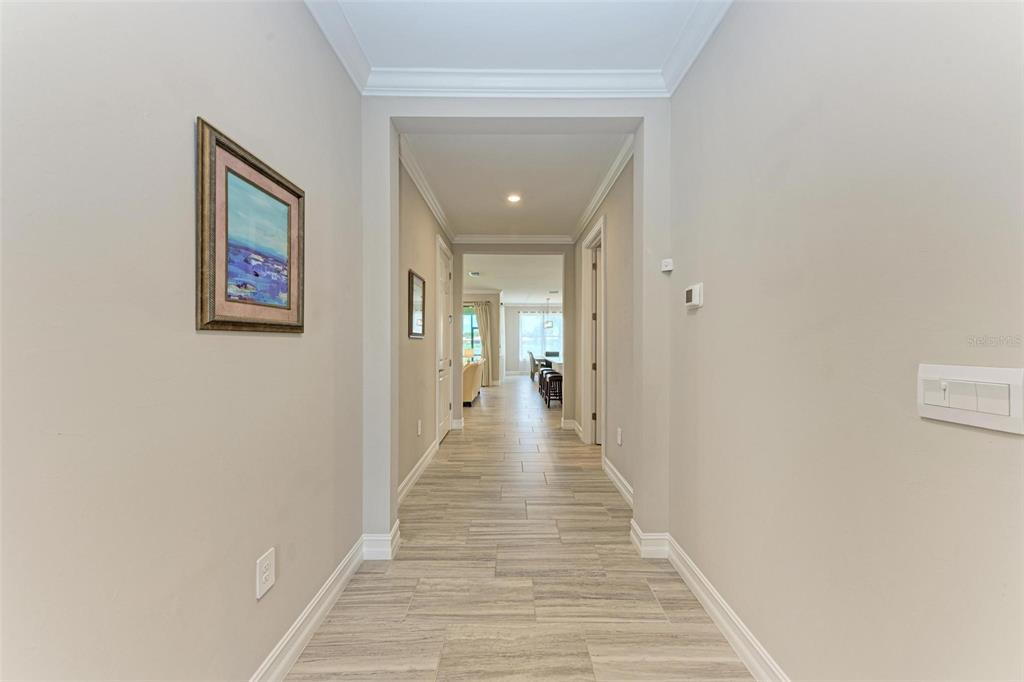 A hallway with light-colored walls and wood-look tile flooring leads toward an open living area — 244 VILLORESI BOULEVARD, NOKOMIS, FL
