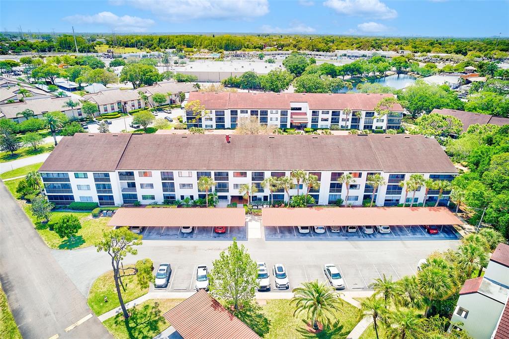 An aerial view shows a multi-story apartment building with covered parking and surrounding landscaping — 2593 COUNTRYSIDE BOULEVARD UNIT 7206, CLEARWATER, FL