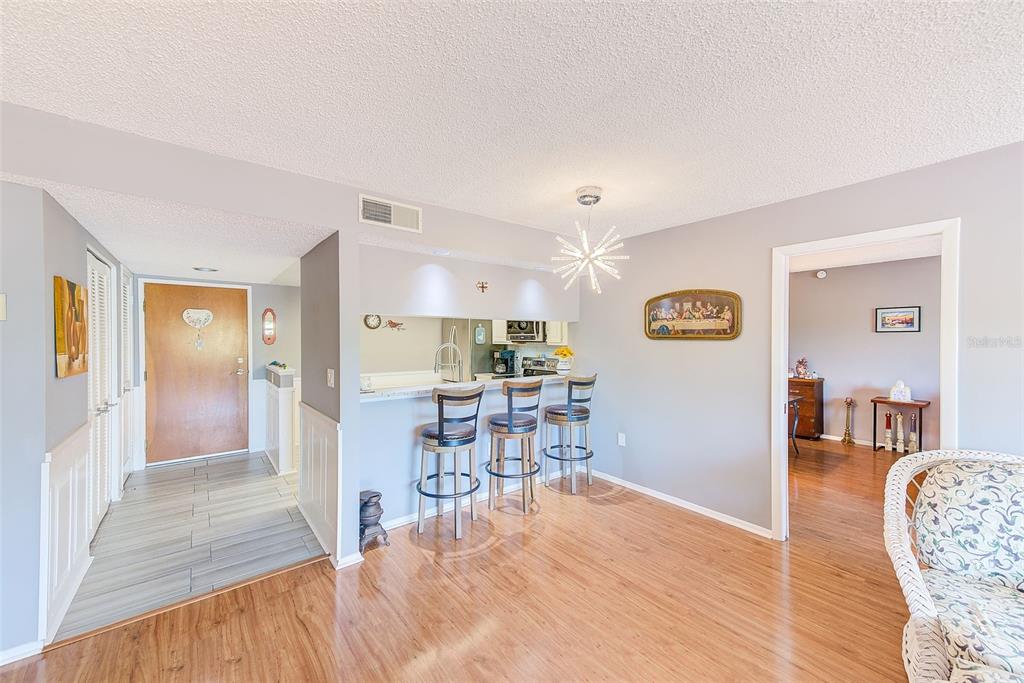 A dining area with wood-look flooring, a breakfast bar with three stools, and a chandelier — 2593 COUNTRYSIDE BOULEVARD UNIT 7206, CLEARWATER, FL