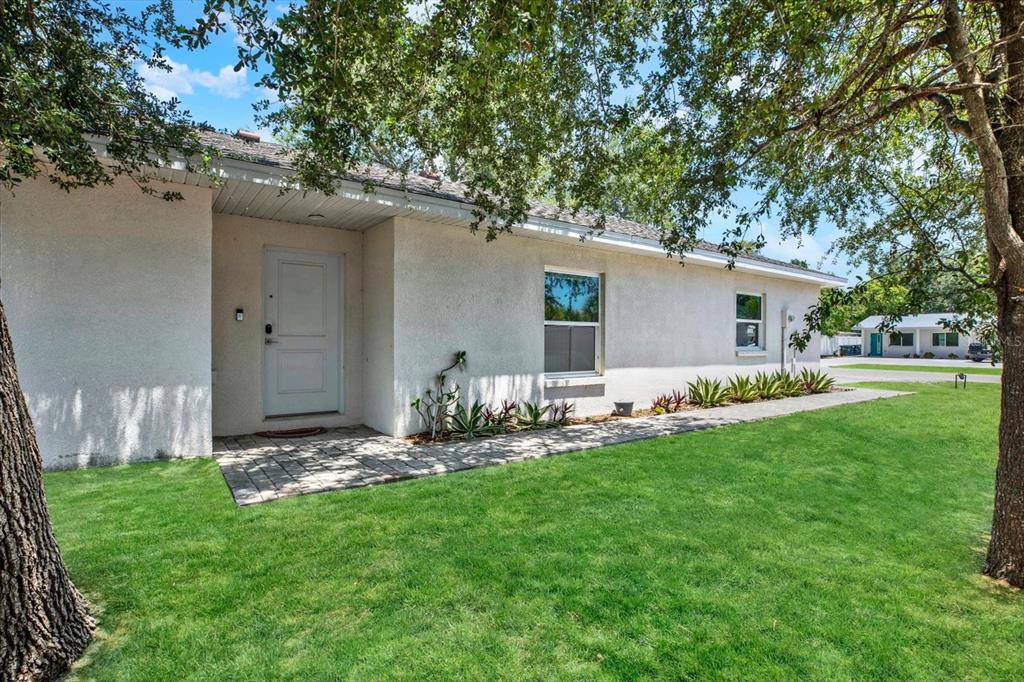 A white stucco house exterior features a front door, a paved walkway, and green lawn — 2011 OUTER DRIVE, SARASOTA, FL
