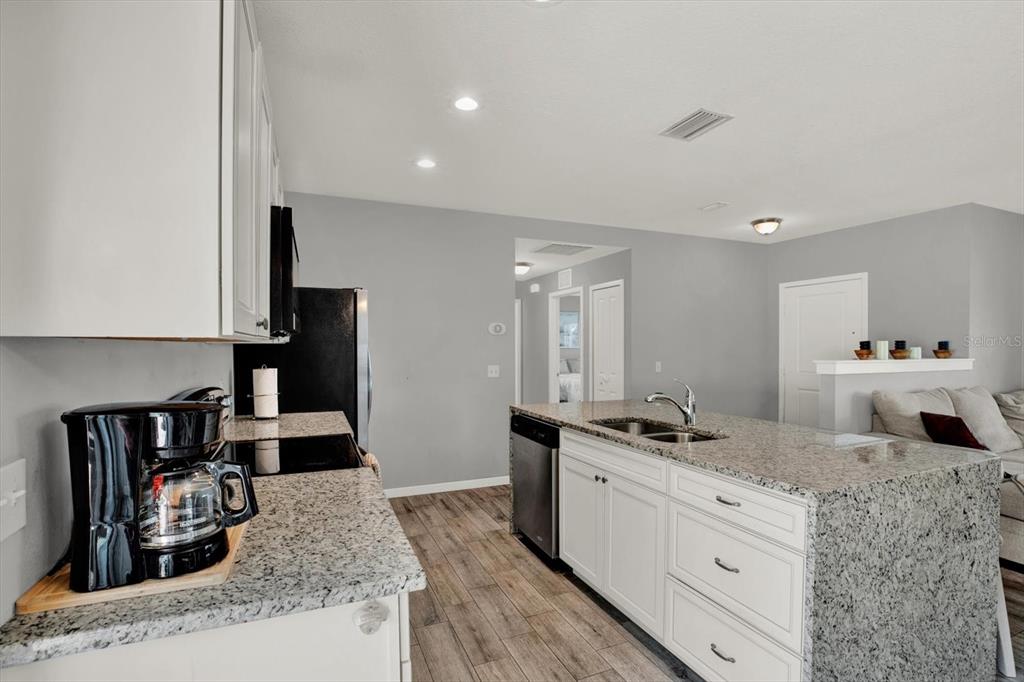 A kitchen with white cabinets, granite countertops, and an island overlooking a living area — 2011 OUTER DRIVE, SARASOTA, FL