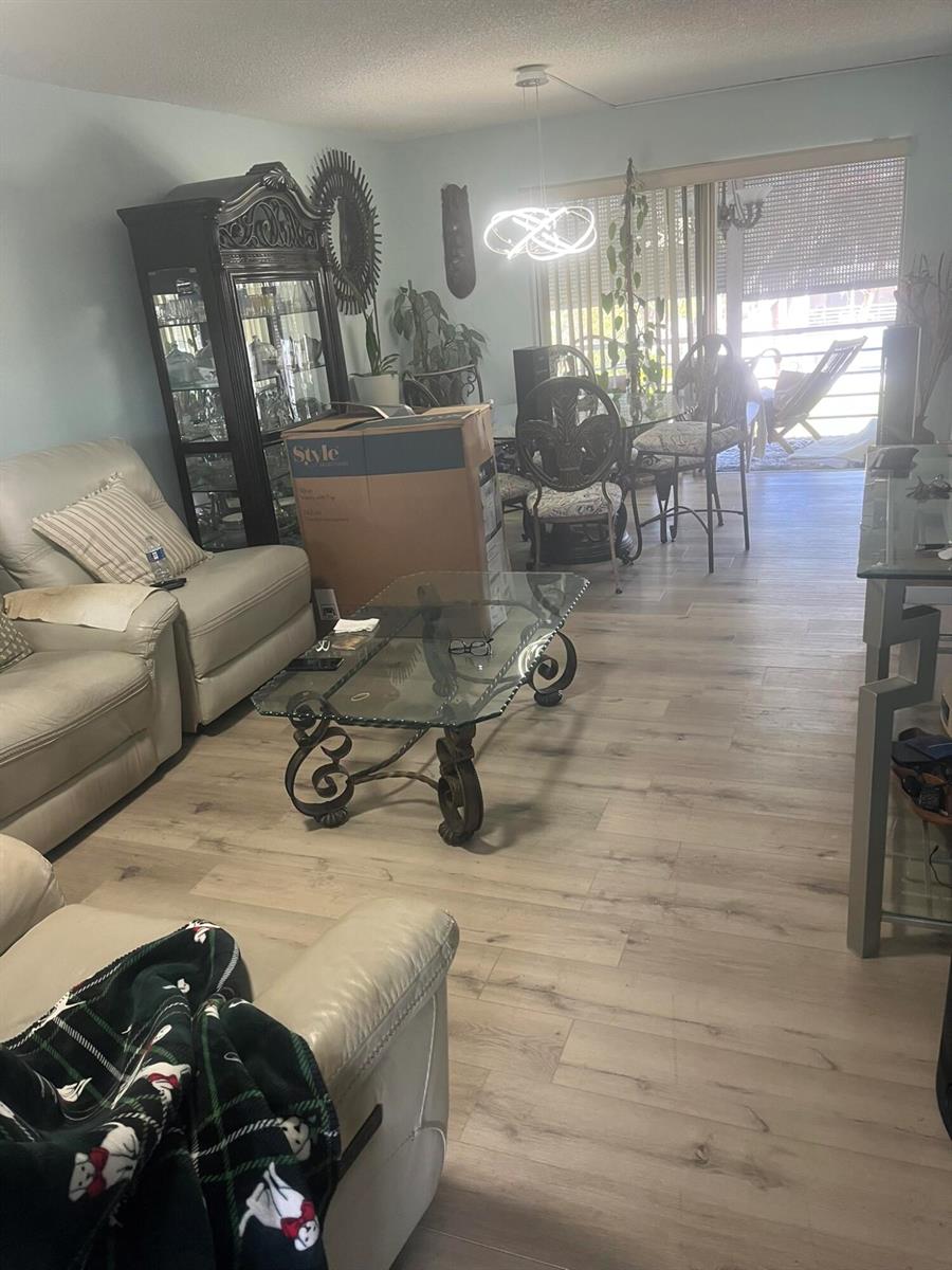 A living and dining area features light wood-look flooring, a glass coffee table, and furniture — 3531 Inverrary Drive # 308, Lauderhill FL 33319, LAUDERHILL, FL