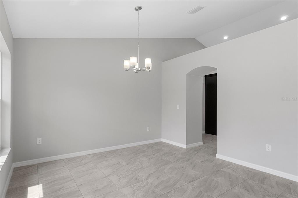 An open-concept kitchen with dark cabinets and a large island overlooks a spacious tiled area — 11367 LATCHWOOD AVENUE, WEEKI WACHEE, FL