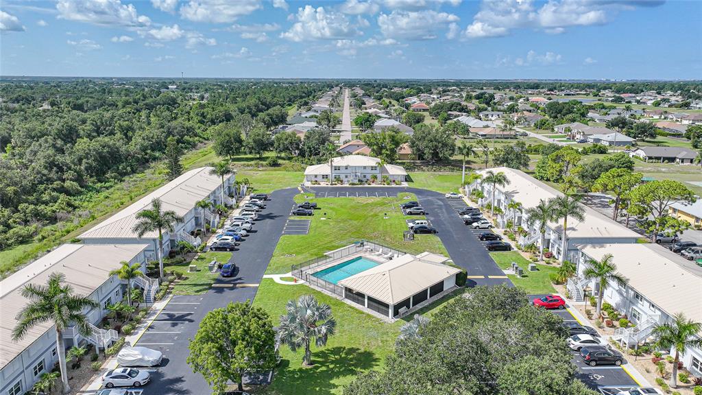 An aerial view shows a multi-building apartment complex with a central swimming pool and parking — 26485 RAMPART BOULEVARD UNIT D4, PUNTA GORDA, FL