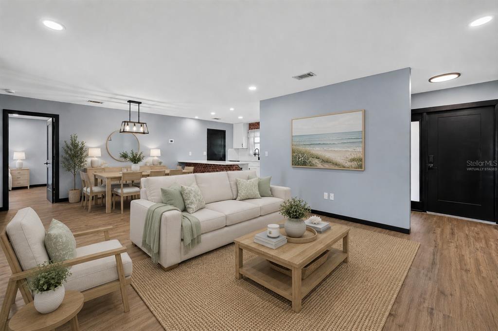 An open-concept living area features light blue walls, wood-look flooring, and a brick-accented kitchen island — 27072 HILLSHIRE LANE, PUNTA GORDA, FL