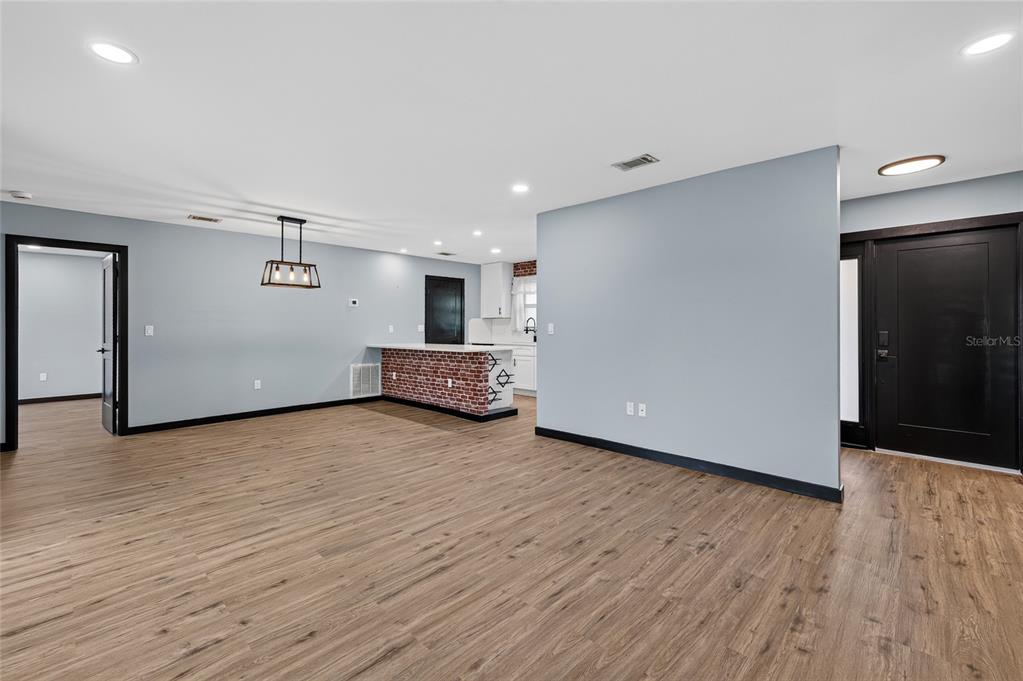 An open-concept living and dining area features a brick-accented kitchen and a fireplace — 27072 HILLSHIRE LANE, PUNTA GORDA, FL