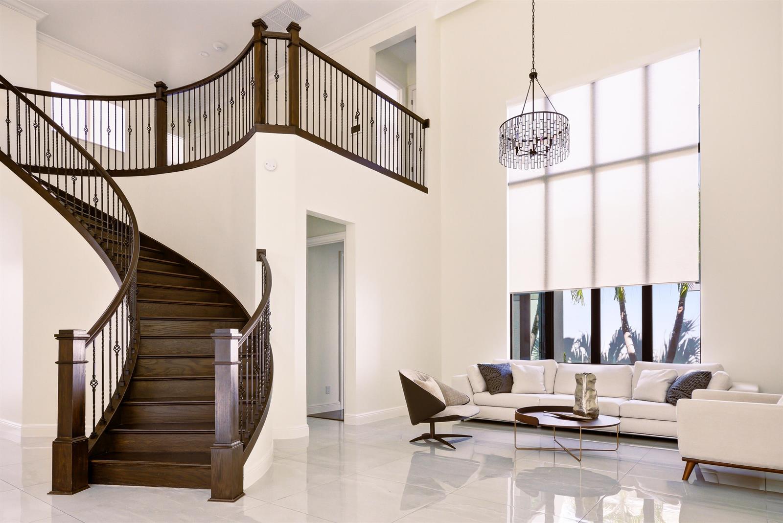 A modern living room features a high ceiling, a staircase, and large windows with blinds — 2630 NW 69th Street, Boca Raton FL 33496, BOCA RATON, FL