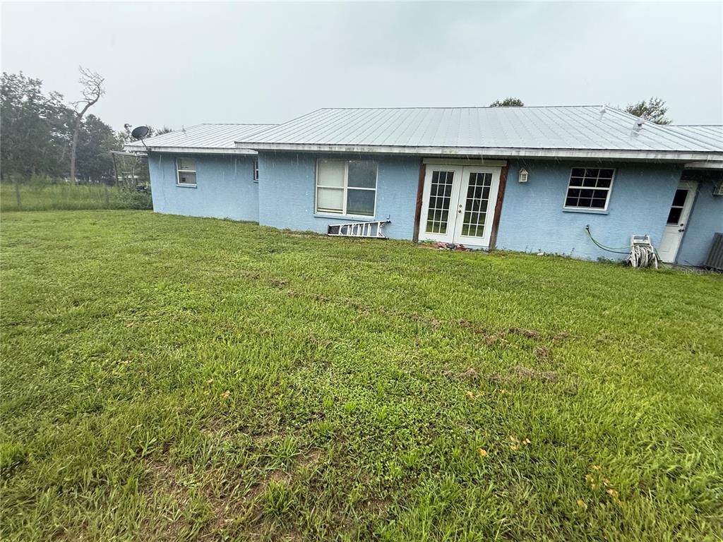 The exterior of a light blue house with a metal roof and a grassy yard — 2480 NW GENES LITTLE ACRES AVENUE, ARCADIA, FL