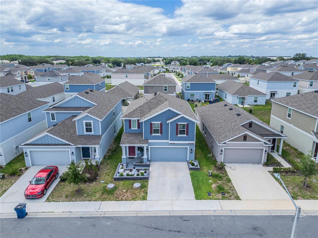 An aerial view shows three suburban houses with blue and gray siding and attached garages — 2158 AQUIFER LANE, DAVENPORT, FL