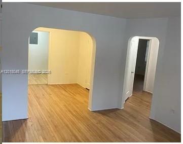An interior view showing two arched doorways leading to other rooms with light wood flooring — 23 Majorca Ave # 1, Coral Gables FL 33134, CORAL GABLES, FL