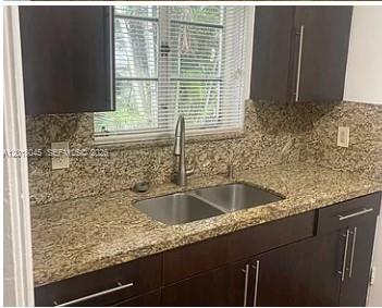 A kitchen features dark wood cabinets, granite countertops, and a stainless steel double-basin sink — 23 Majorca Ave # 1, Coral Gables FL 33134, CORAL GABLES, FL