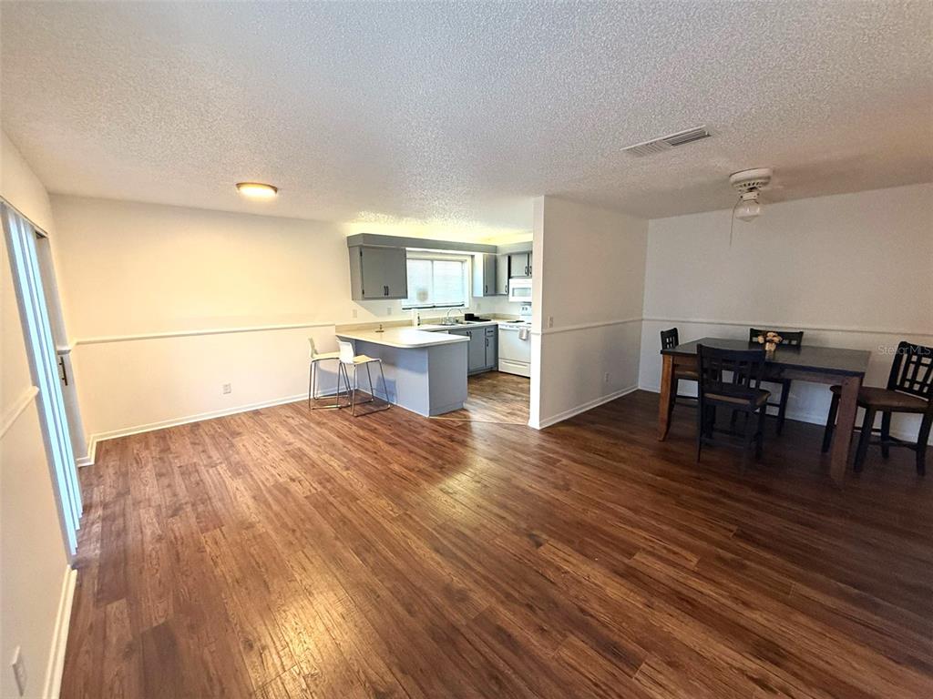 An open-concept living and dining area features wood-look flooring and a kitchen with gray cabinets — 1406 PARK SHORE CIRCLE UNIT 3, FORT MYERS, FL