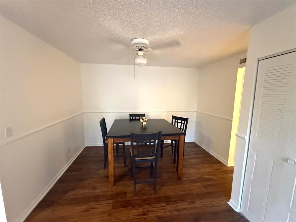 A dining room features dark wood flooring, white walls with chair rail molding, and a ceiling fan — 1406 PARK SHORE CIRCLE UNIT 3, FORT MYERS, FL