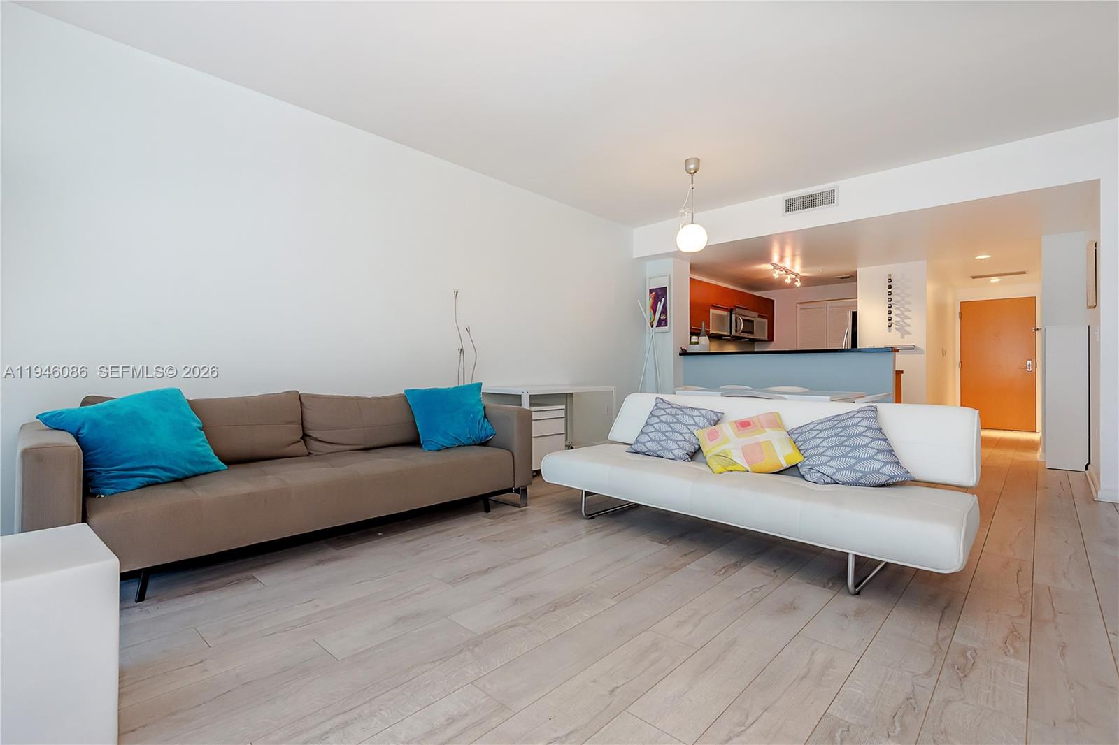 A living room features a brown sofa, a white futon, and light wood-look flooring — 253 NE 2nd St # 907, Miami FL 33132, MIAMI, FL