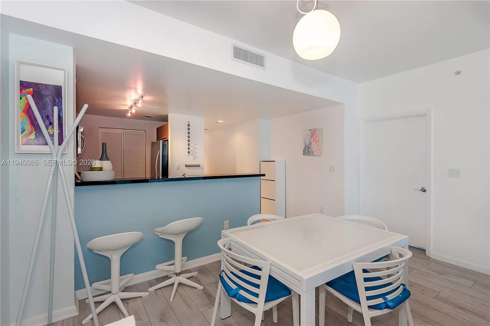 A dining area with a white table, four chairs, and a blue breakfast bar — 253 NE 2nd St # 907, Miami FL 33132, MIAMI, FL