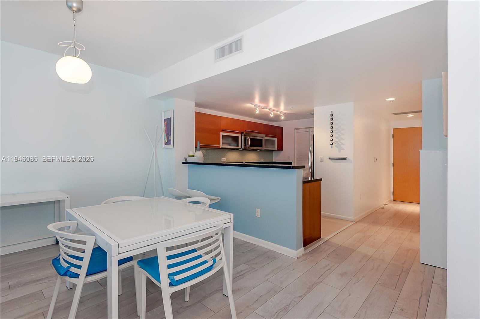 A dining area with a white table and chairs sits adjacent to a blue kitchen — 253 NE 2nd St # 907, Miami FL 33132, MIAMI, FL