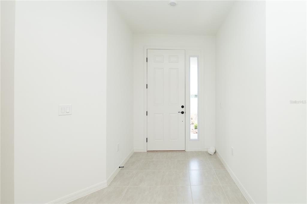 A bright entryway features white walls, a white front door with a sidelight, and tile flooring — 3108 EVELYN LANE, BARTOW, FL