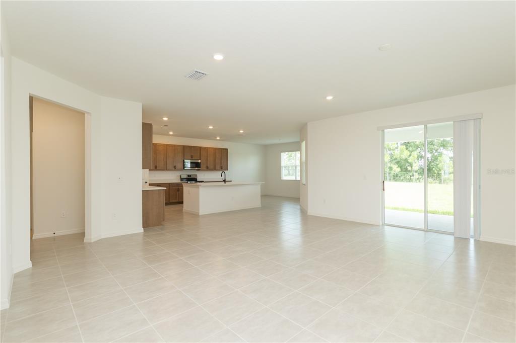 An open-concept kitchen and living area with light tile flooring and sliding glass doors — 3108 EVELYN LANE, BARTOW, FL