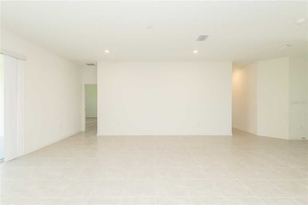 An empty room with white walls, light tile flooring, and a sliding glass door — 3108 EVELYN LANE, BARTOW, FL